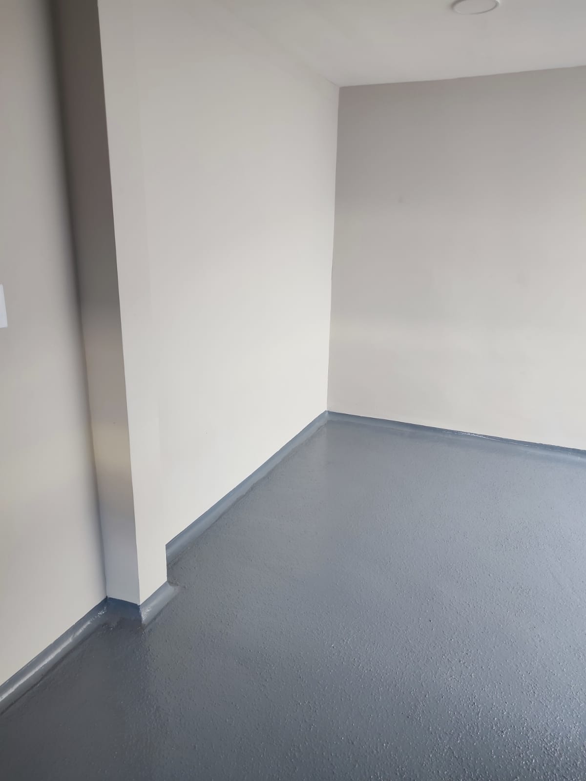 11. Detalle del zoclo sanitario. Vista cercana de la unión curva entre el piso y el muro, facilitando la limpieza y evitando la acumulación de suciedad.
