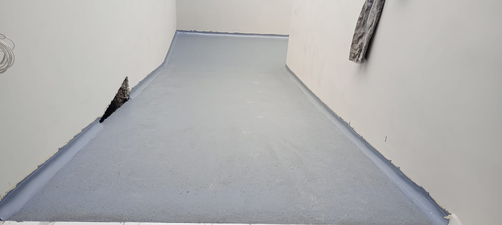 5. Formación del zoclo sanitario. El recubrimiento se extiende hacia la parte inferior de los muros, formando una curva continua entre el piso y la pared.