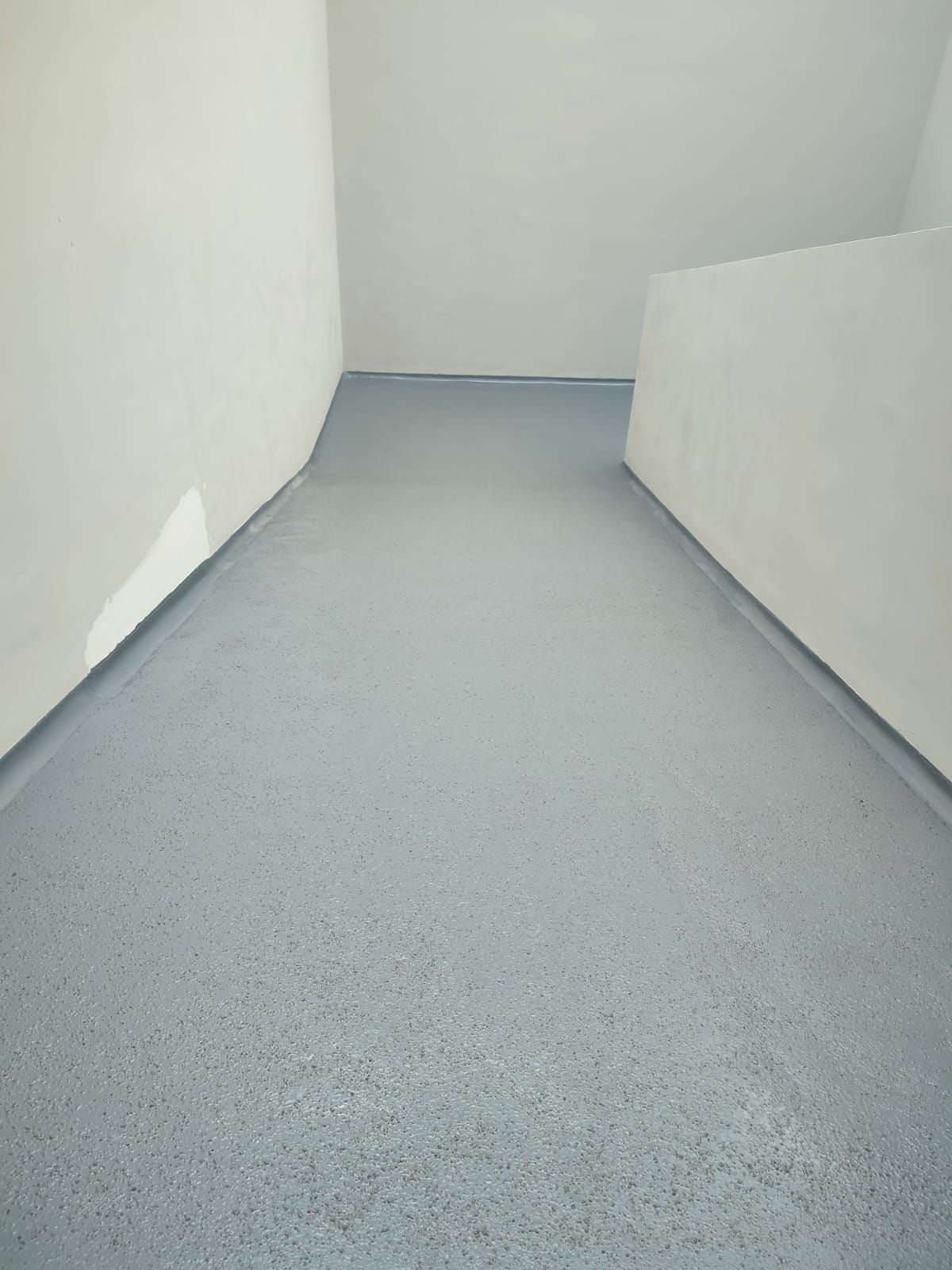 8. Acabado antiderrapante en pasillo. Vista del piso con textura antiderrapante y zoclo sanitario aplicado alrededor de los muros.